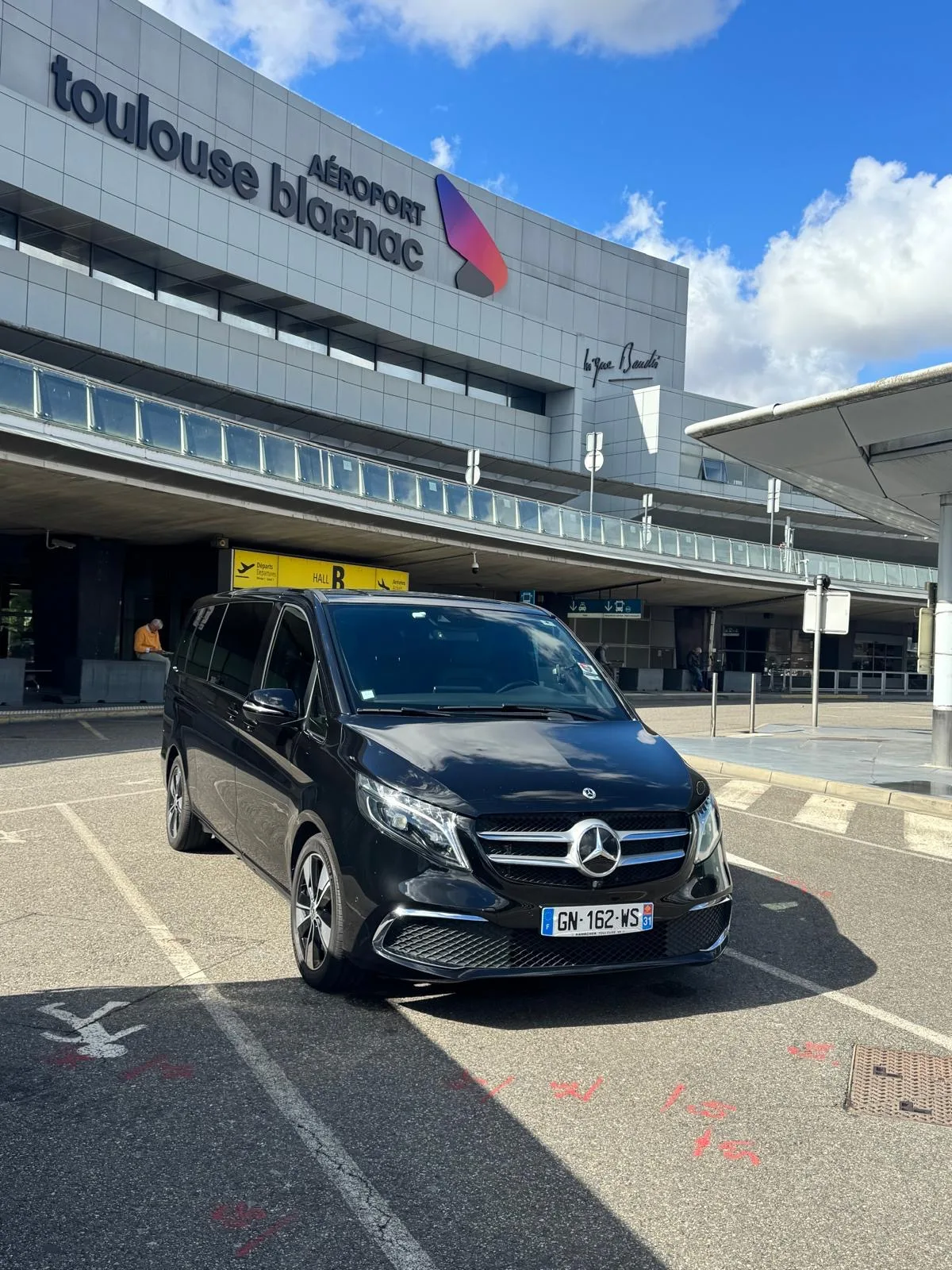 Van Mercedes Classe V noir de Toulouse VTC Pro garé devant le terminal de l’aéroport Toulouse-Blagnac, hall B
