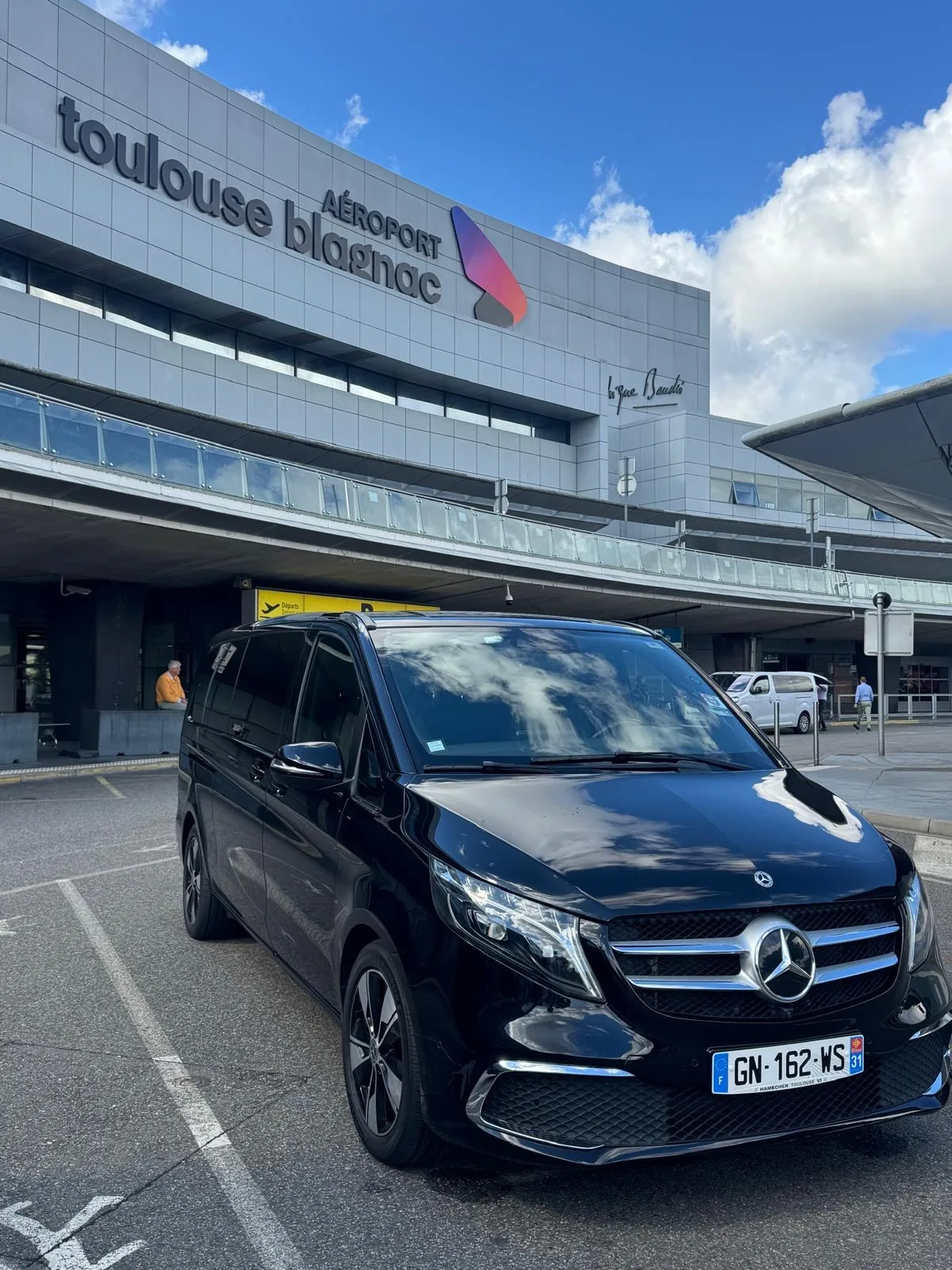 VTC van Mercedes Classe V noir devant le terminal de l’aéroport Toulouse-Blagnac — van avec chauffeur privé pour groupes et familles