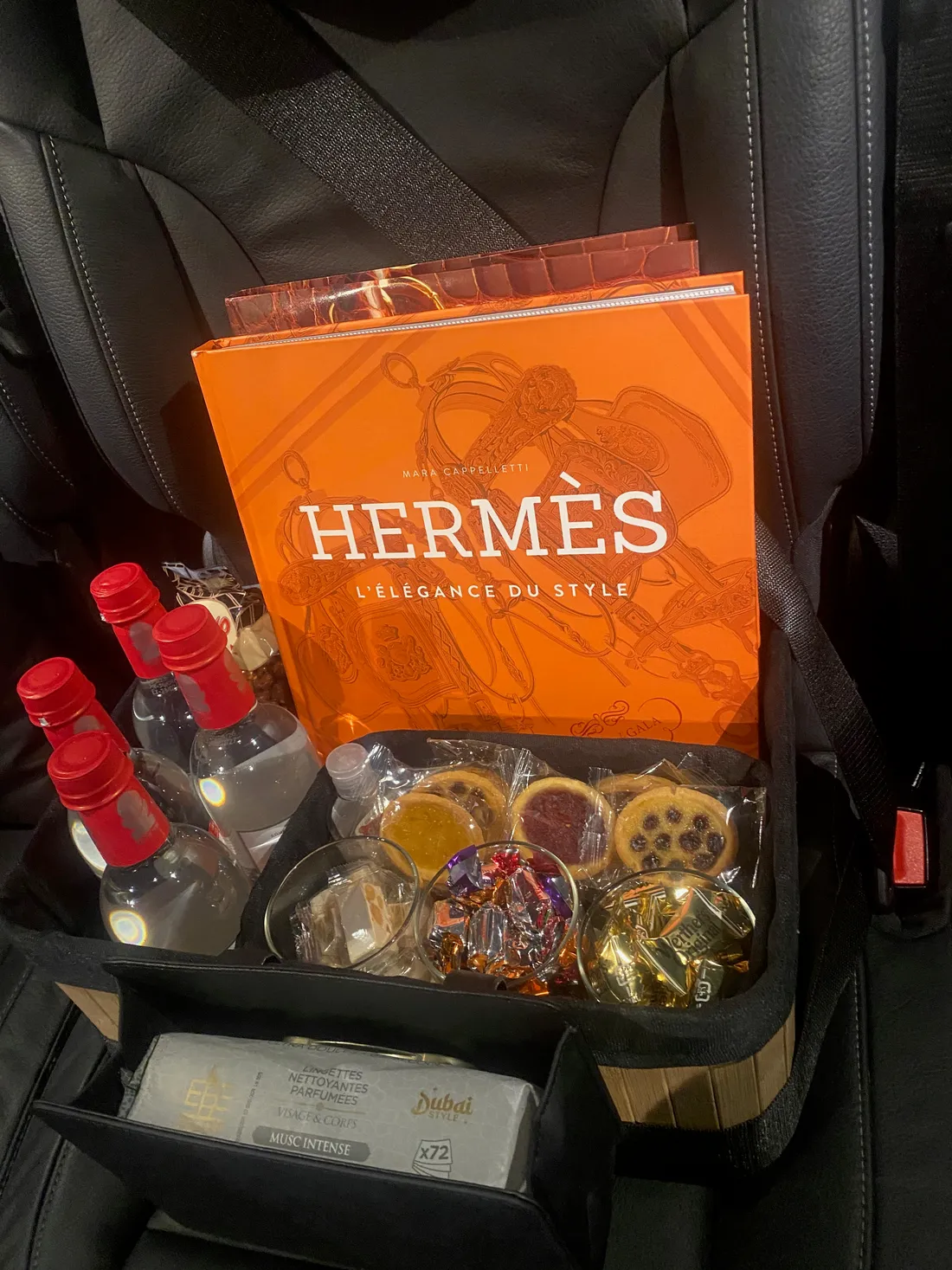 Panier d’attentions à bord du van de Toulouse VTC Pro — bouteilles d’eau, petits gâteaux, bonbons, lingettes rafraîchissantes et un livre à feuilleter
